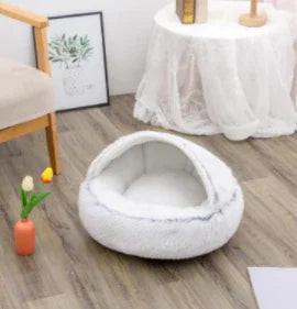 Cozy white plush pet bed with hood on wooden floor in a modern living room setting