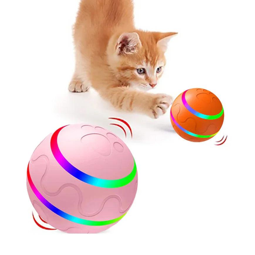 Orange kitten playing with interactive LED cat toy balls on a white background