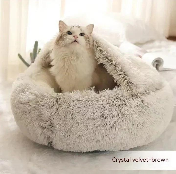 Fluffy white cat in a soft crystal velvet brown covered cat bed on a cozy indoor surface