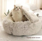 Fluffy white cat in a soft crystal velvet brown covered cat bed on a cozy indoor surface