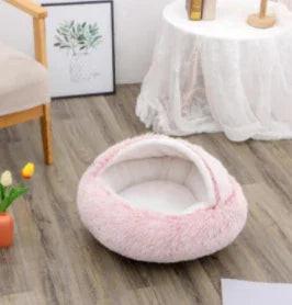 Soft pink cat or dog cave bed in cozy living room setting with wood floor
