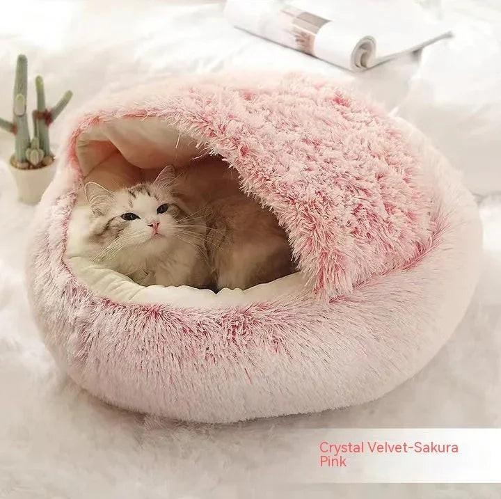 Cat resting in a pink crystal velvet covered pet bed on a white surface