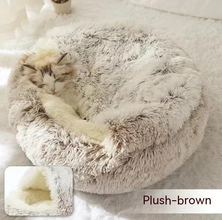 Cat sleeping in round plush brown pet bed on soft white surface